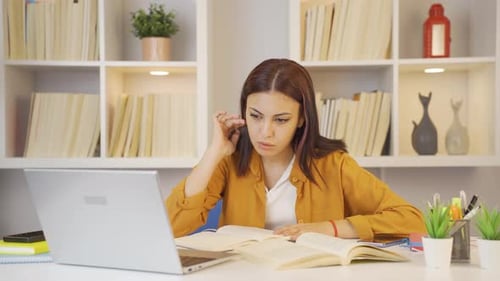 Focused Student Studying at Desk with Laptop and Book