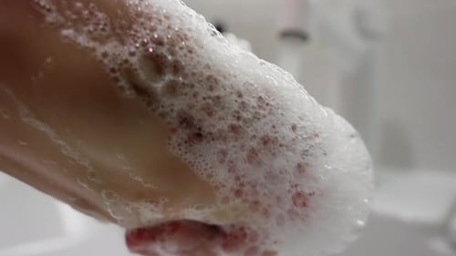 Woman washing hands with soap in bathroom
