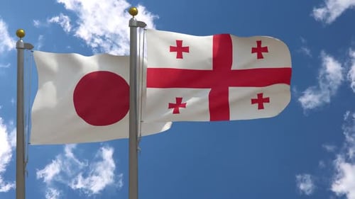 Japan and Georgia Flags Waving on Flagpoles Against Blue Sky