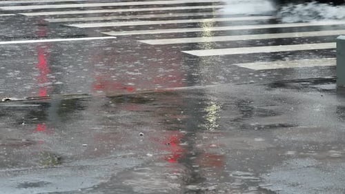 Autoreifen spritzt während eines heftigen Regensturms Wasser auf den nassen Stadtasphalt