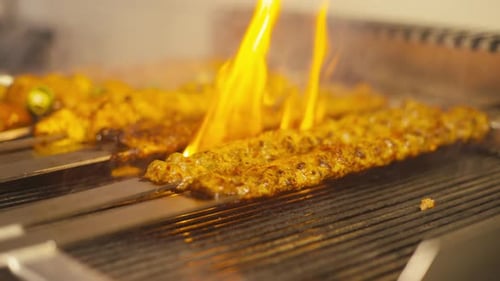 Flame-grilled kebab cooking on a grill, vibrant fire detail