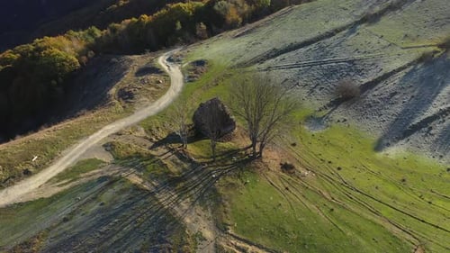 Flying above autumn rural remote mountain hut with thatched roof aerial