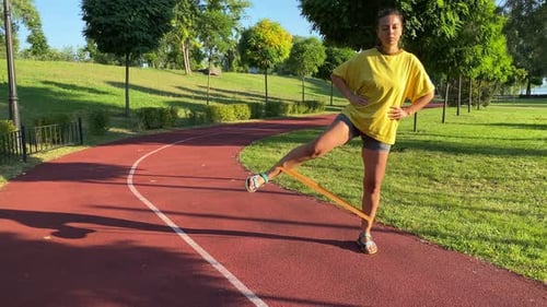 Young Woman Enhances Fitness with Resistance Band Stretches in Park