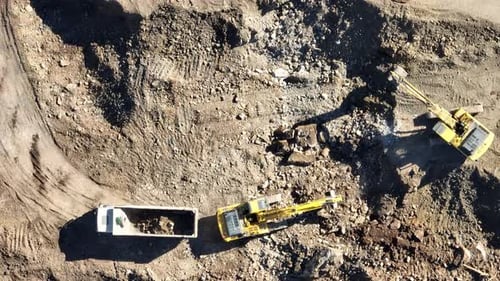 Industrial Mine Excavators are Digging the Soil in the Construction Site and Loading Trucks