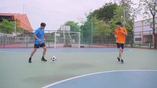 Asian young sportsman practicing football playing in the outdoors stadium.