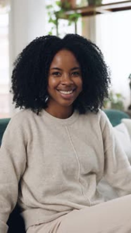 Woman Smiling in Cozy Clothing, Sitting on Couch