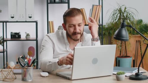 Man Looks at Computer and Closes Laptop at Desk