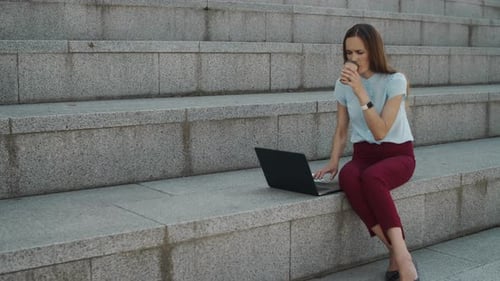 Professional Woman Works on Laptop, Drinks Coffee Outdoors