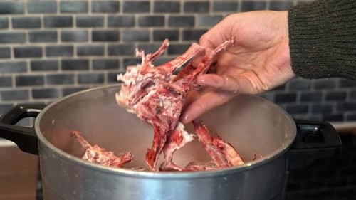 Hand Sorts Raw Meat Bones in Silver Cooking Pot