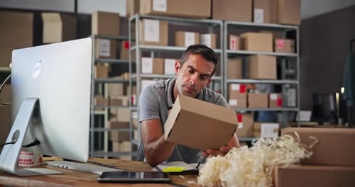 Man holding box in office looking at computer