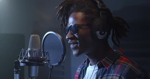 Close Up Portrait of Young Male Black Singer with Headphones Recording an Album in Profes