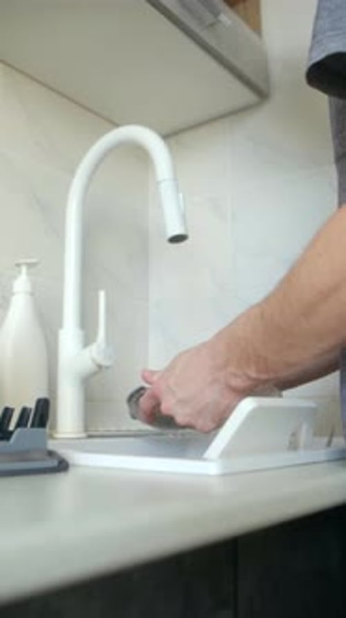 Man Washing Dishes in Modern Kitchen Sink