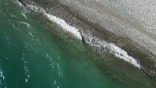 Top View of Waves Break on Empty Pebble Beach Pure Calm Sea From Bird's Eye View