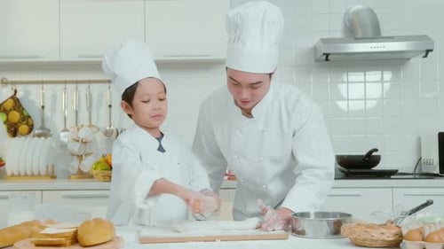 Child and Adult Baking Bread Together in Kitchen