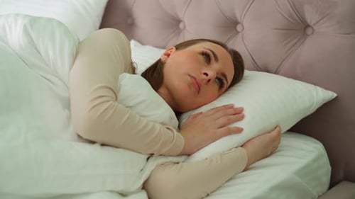 Woman Resting Peacefully in White Bedroom
