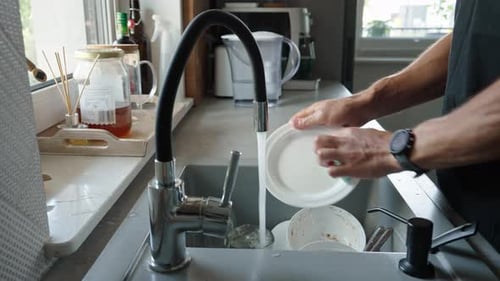 Man Washing Dishes in a Kitchen Sink