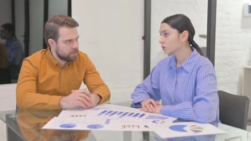 Two Colleagues Discussing Data in Modern Workplace