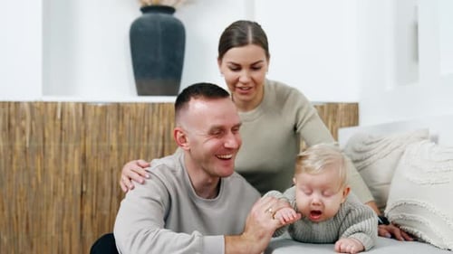 Happy Family Smiling With Infant Baby on Couch