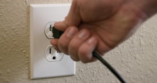 Close Up Side of Man's Hand Plugging Cord Into Electrical Outlet Then Unplugging in Slow Motion
