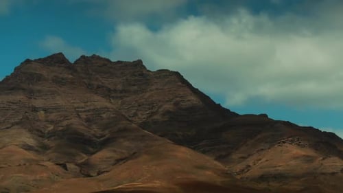Timelapse of a rocky mountain with clouds crossing the wind.