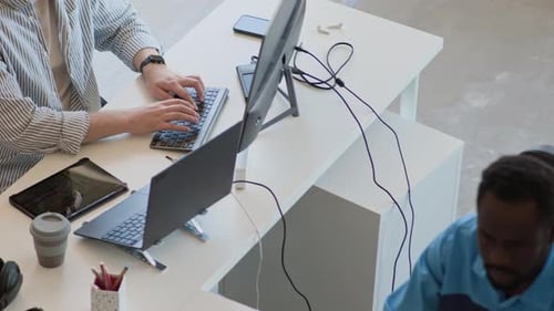 Two Biracial Men Typing On Computers In Office