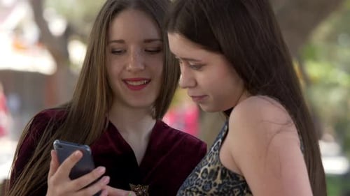 Two Stylish Women Using Smartphone Outdoors