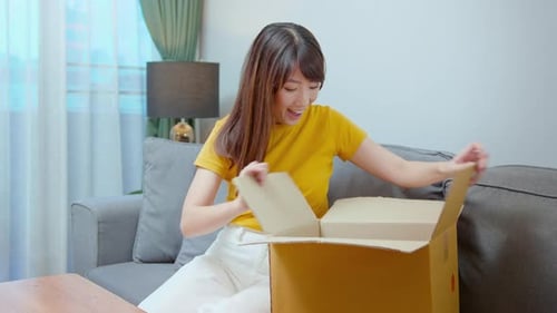 Woman Excitedly Opens a Box on the Couch