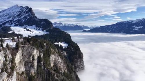 rugged swiss cliffs descend into a glowing cloud ocean beneath snowy alpine ridges