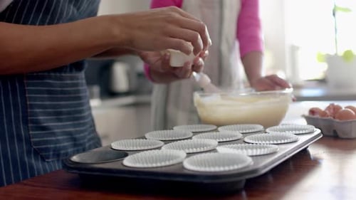 Mittelteil von Mutter und Tochter beim Kuchenbacken in der Küche, Kopierraum, Zeitlupe
