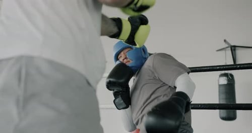 Zwei junge Boxer trainieren zusammen und trainieren im Fitnessstudio und schlagen mit Handschuhen und Helmen
