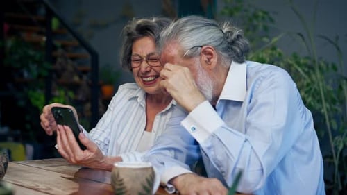 Senior Couple Laughing at Smartphone at Home