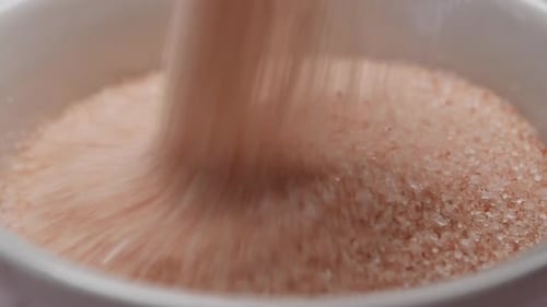 Raw Whole Dried Pink Himalayan Salt in a Container on White