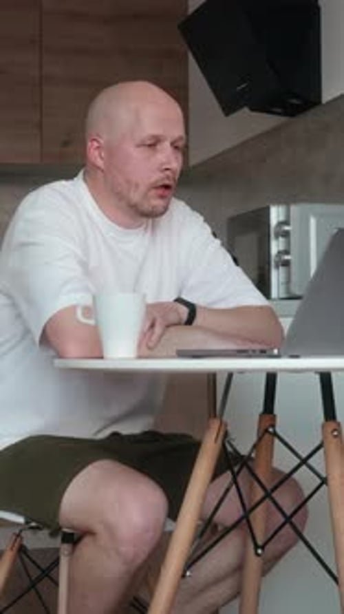 Man Video Calling on Laptop in Kitchen at Home