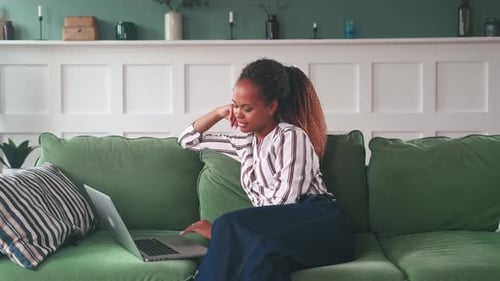 Woman Works Thoughtfully from Home on Laptop