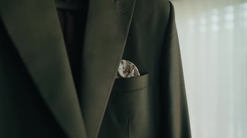 elegant dark suit with floral pocket square hanging in soft light