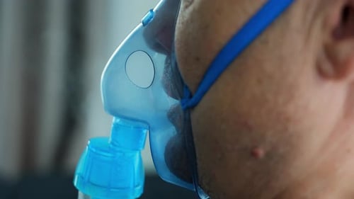 Vue rapprochée d'un homme en mauvaise santé portant un masque de nébulisation respirant à domicile, équipement médical de santé et
