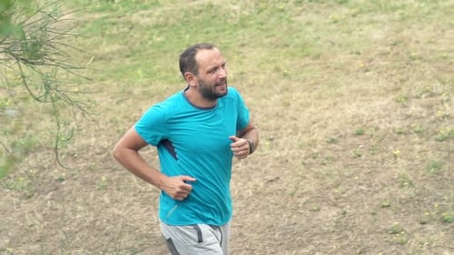 Handsome young man jogging in park training for London marathon in super slow motion