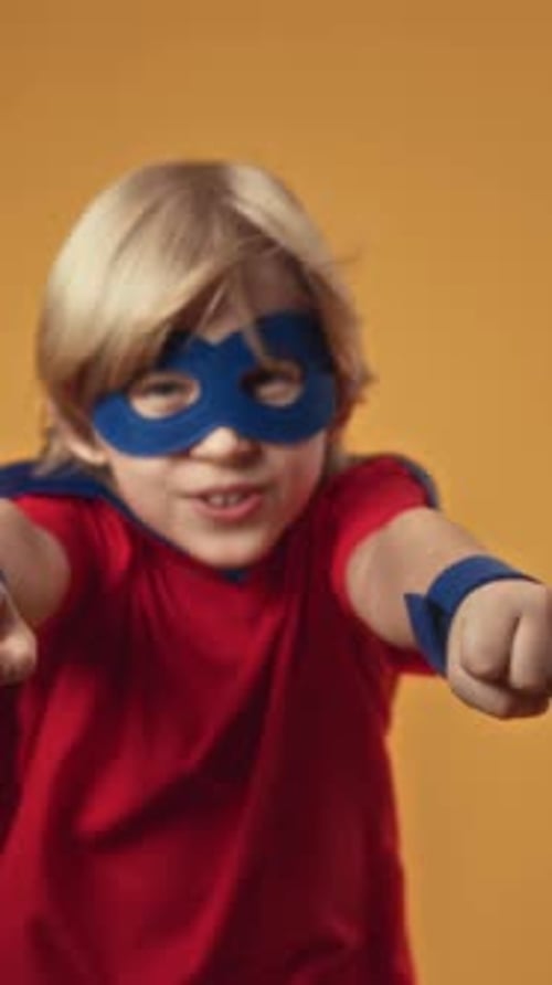 Vertical Studio Portrait of Boy in Superhero Costume Flying with Arms Forward