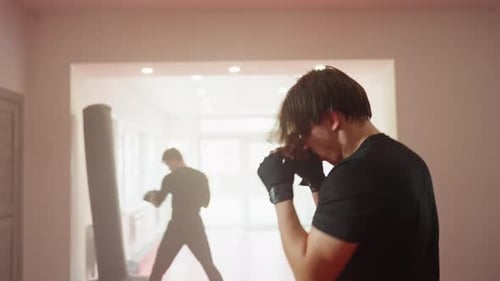 Athlete in Black Sportswear Trains with Intensity Inside Gym Throwing Fast Punches