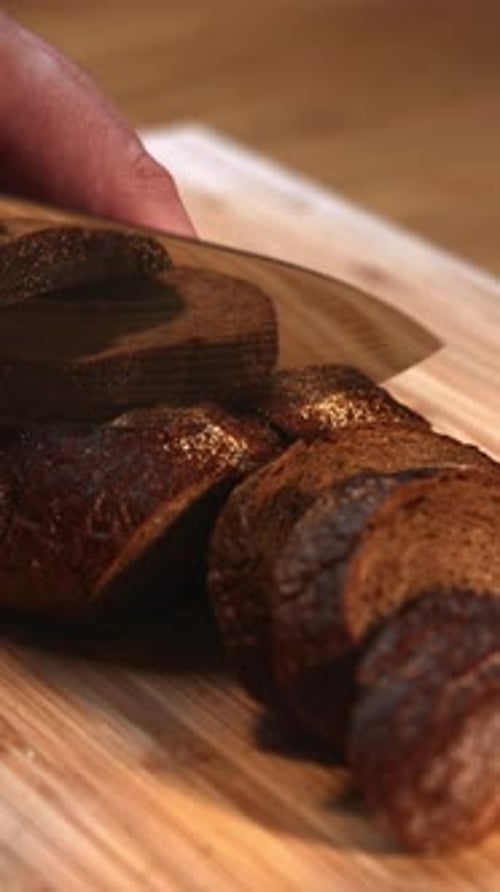 Loaf of Dark Bread Sliced on Cutting Board