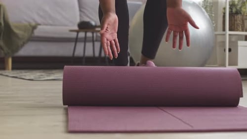 Black Woman Rolling up Mat after Sports Training Low Section