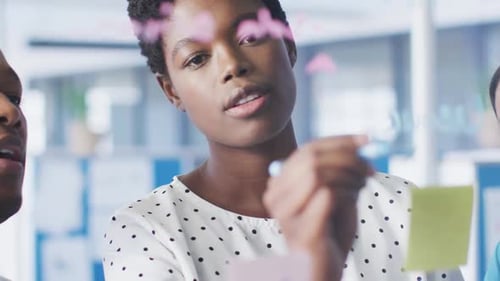 Empresários afro-americanos discutindo e escrevendo em placa de vidro no escritório, em câmera lenta