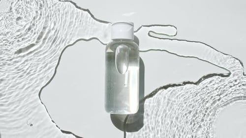 Clear Bottle Surrounded by Rippling Water