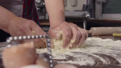 Hands Kneading Dough on Flour-Covered Wooden Surface
