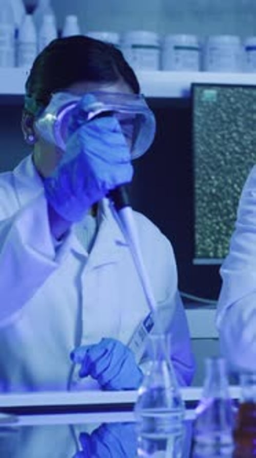 Woman Scientist Pipetting Liquid in Laboratory Research Setting