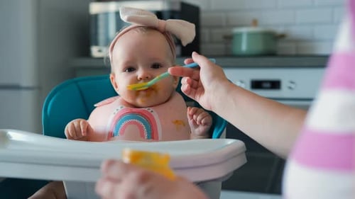 Adorable Infant Being Fed in Kitchen High Chair
