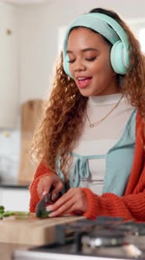 Cheerful Woman Prepares Food in Kitchen with Headphones