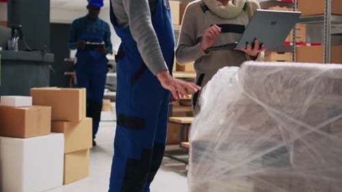 Warehouse Workers Inspecting Packages with Laptop