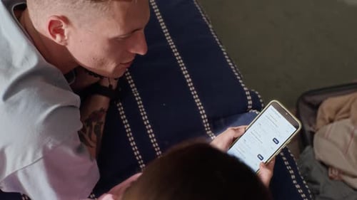 Couple Planning Vacation and Booking Flights on Mobile Phone