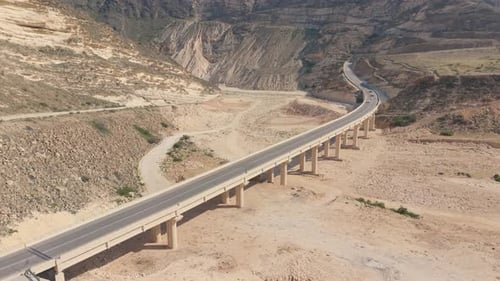 Aerial View of a Long Concrete Viaduct Crossing a Deep Arid Canyon in a Mountainous Desert Region